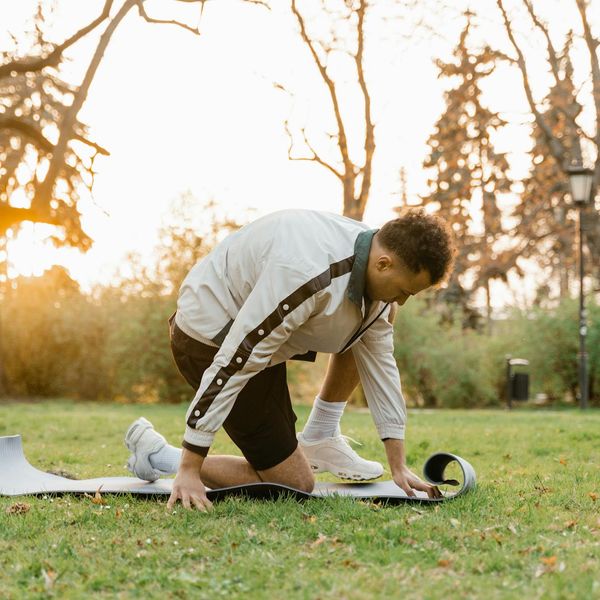 Person in a comfortable athletic wear doing a gentle stretching exercise outdoors at sunrise.